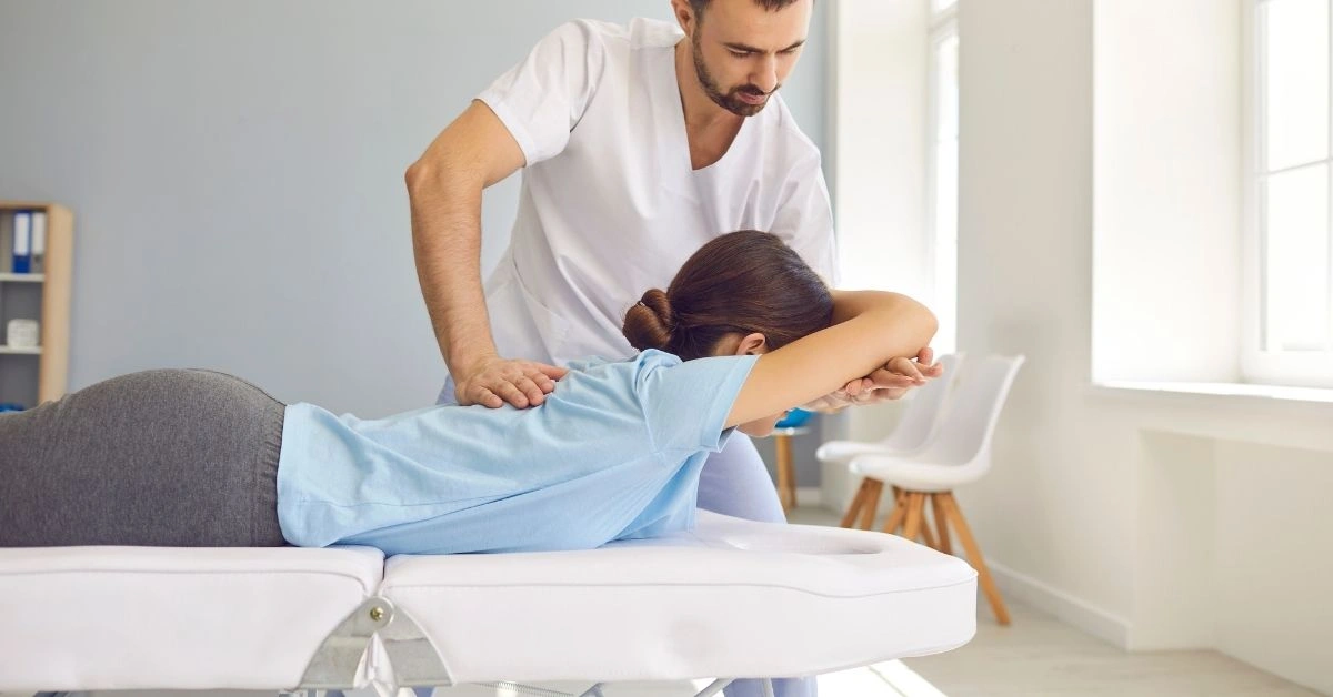 chiropractor-performing-spinal-adjustment-on-woman-lying-face-down-on-treatment-table